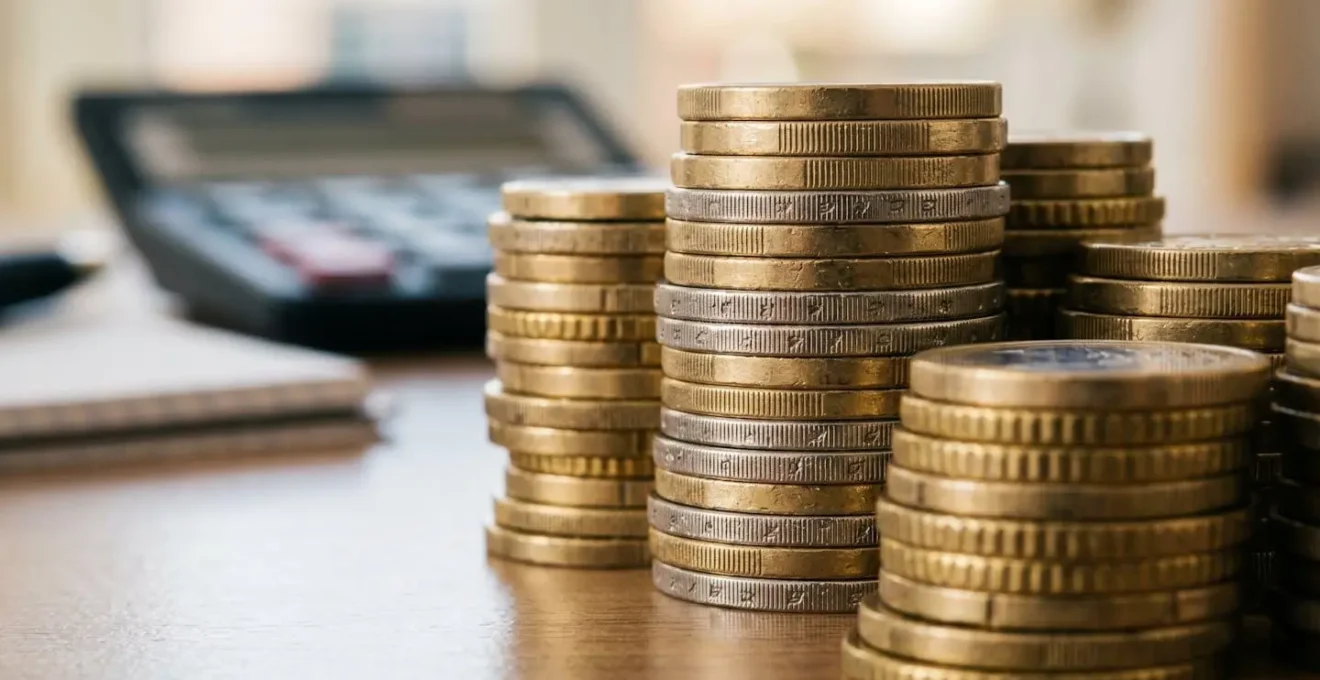 Pièces d'euros empilées avec calculatrice floue en arrière-plan