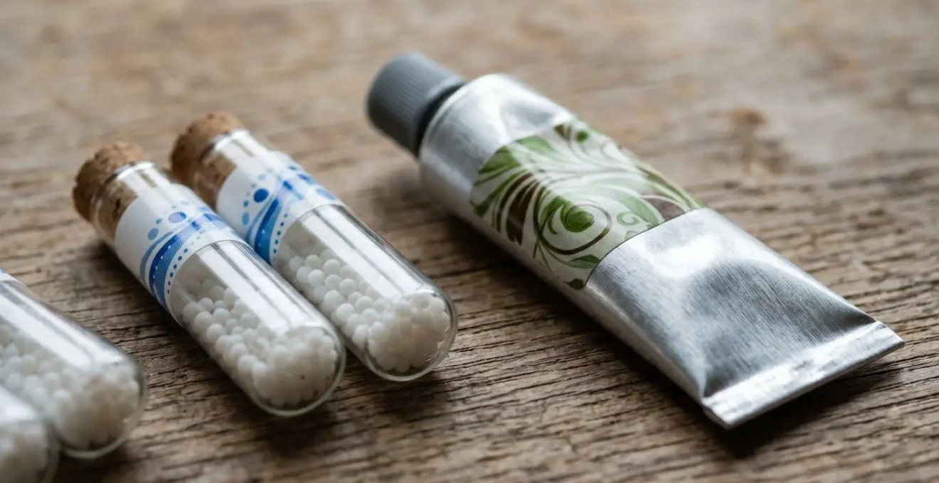 Tubes d'homéopathie et crèmes de phytothérapie disposés côte à côte sur une surface en bois naturel