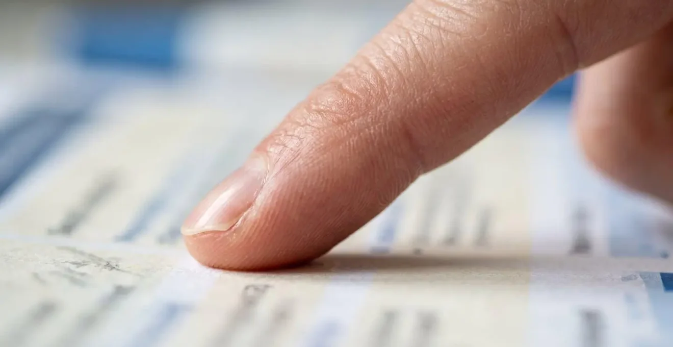 Gros plan macro sur une main pointant une ligne dans un document flou avec mise au point sélective sur le doigt